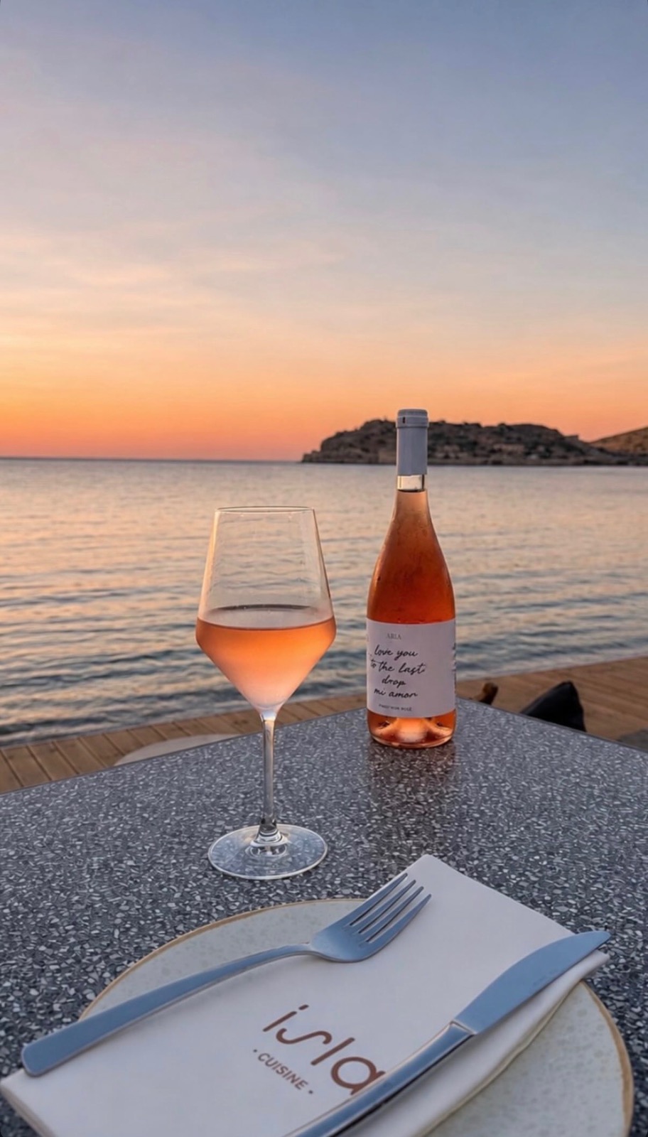 Rosé wine and place setting at Isla Cuisine with Spinalonga sunset